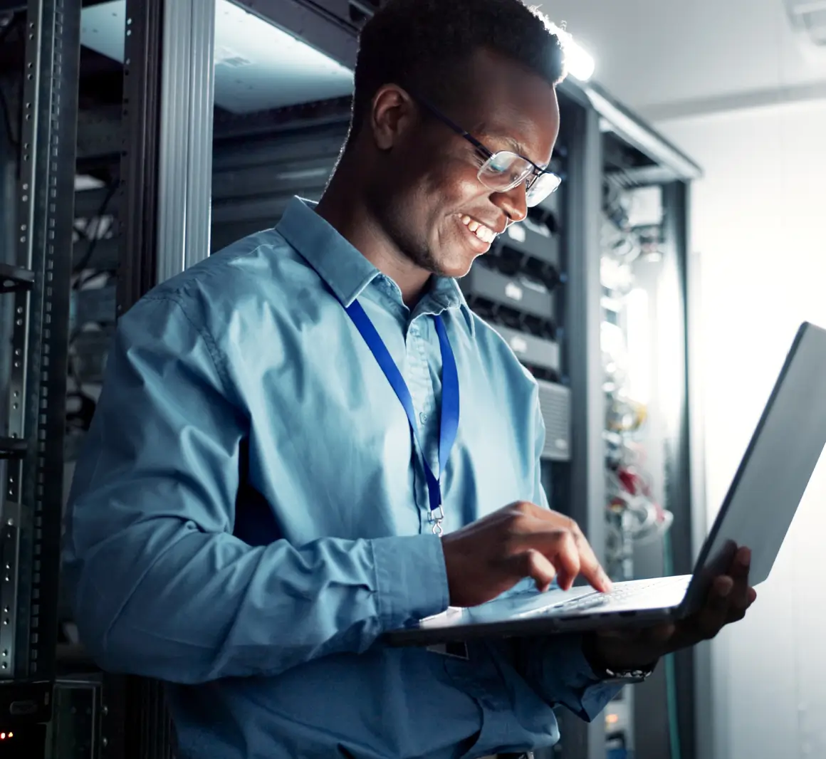 Technician working on laptop in server room.